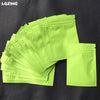 A stack of bright lime green mini reusable ziplock bags laid on a dark surface.