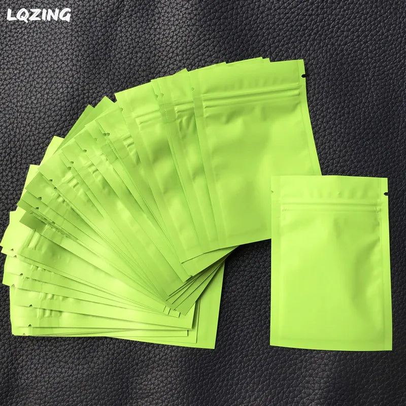 A stack of bright lime green mini reusable ziplock bags laid on a dark surface.