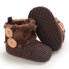 A pair of brown faux fur baby snow boots with anti-slip soles and wooden buttons.