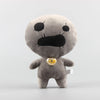 A soft gray plush toy resembling a face with black features and a gold-colored belly button.
