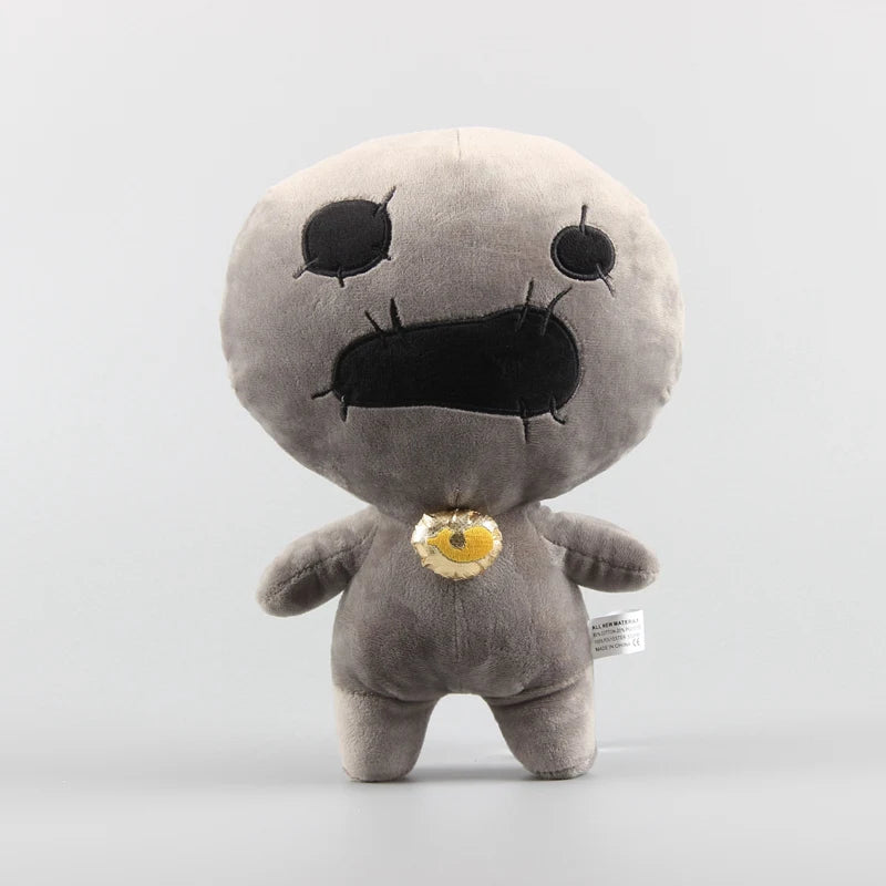 A soft gray plush toy resembling a face with black features and a gold-colored belly button.