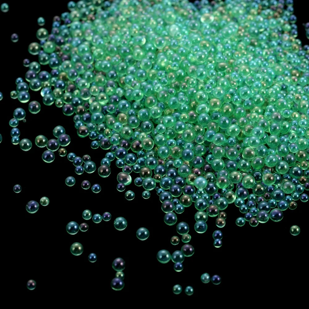 A pile of small, translucent green glass bubble beads scattered against a black background.
