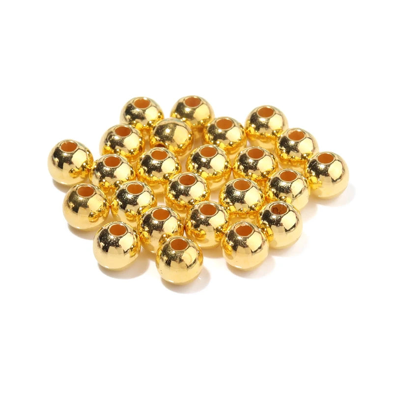 A pile of small, round, gold-colored imitation pearl beads for DIY jewelry making.