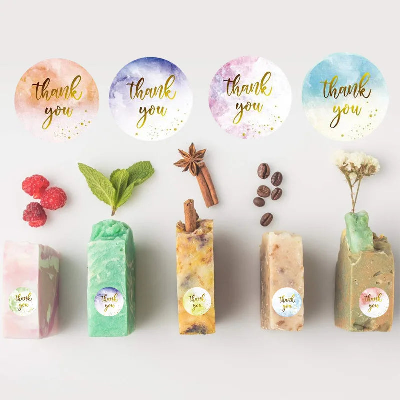 A collection of round, colorful thank you stickers in various shades of pink, purple, and green on a white background.