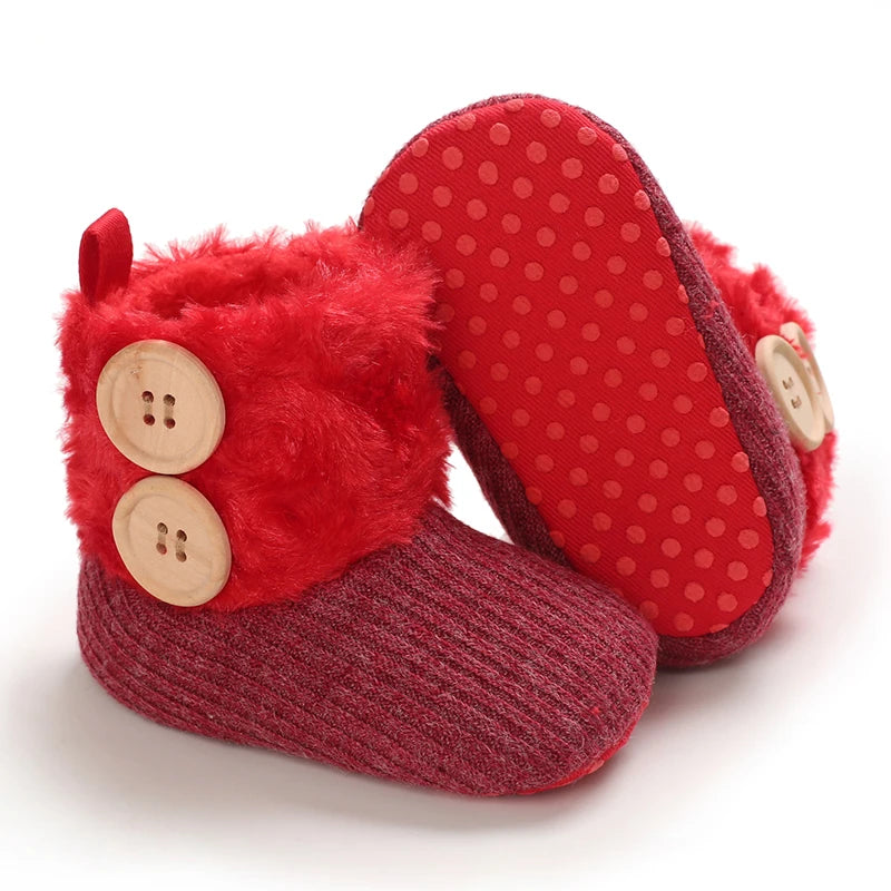 A pair of red plush baby snow boots with fuzzy trim and a red anti-slip sole.