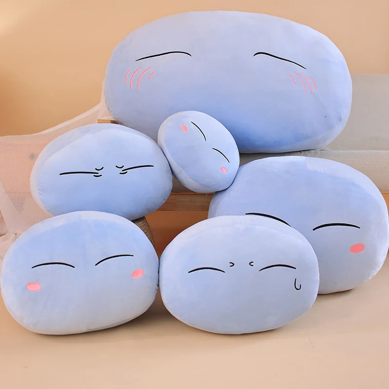 A collection of light blue, squishy plush toys shaped like sleeping anime slime characters.