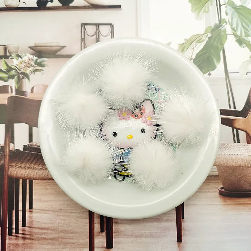 A white ceramic plate holds several fluffy white mink fur pom poms for crafts and accessories.