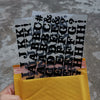 A hand holds a yellow envelope filled with black iron-on heat transfer patches for clothing.