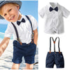 A boy wearing a white shirt, navy shorts, and suspenders for a formal wedding outfit set.