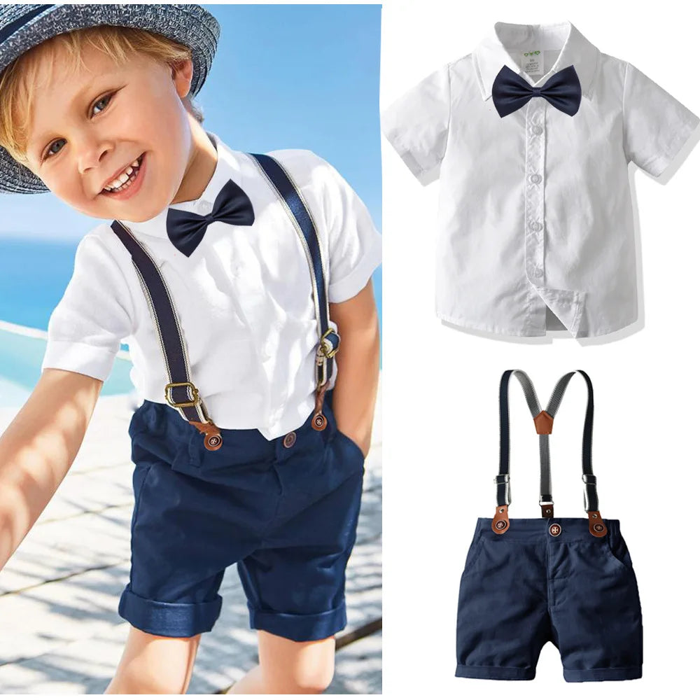 A boy wearing a white shirt, navy shorts, and suspenders for a formal wedding outfit set.