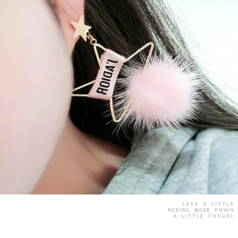 Gold-toned star-shaped earring featuring a pink rectangular charm with the text ROIDA'L and a fluffy pink mink fur pom pom