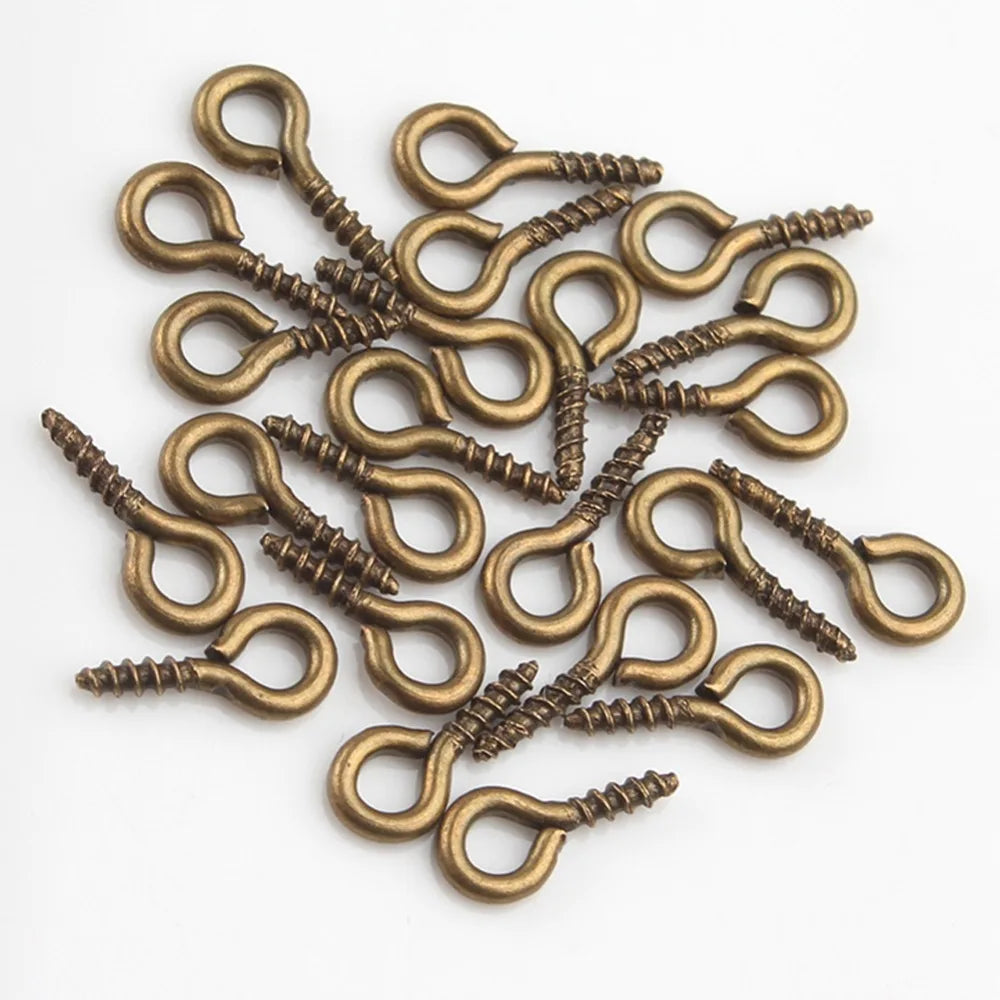 A pile of small brass eye pins with screw threads used for jewelry making.