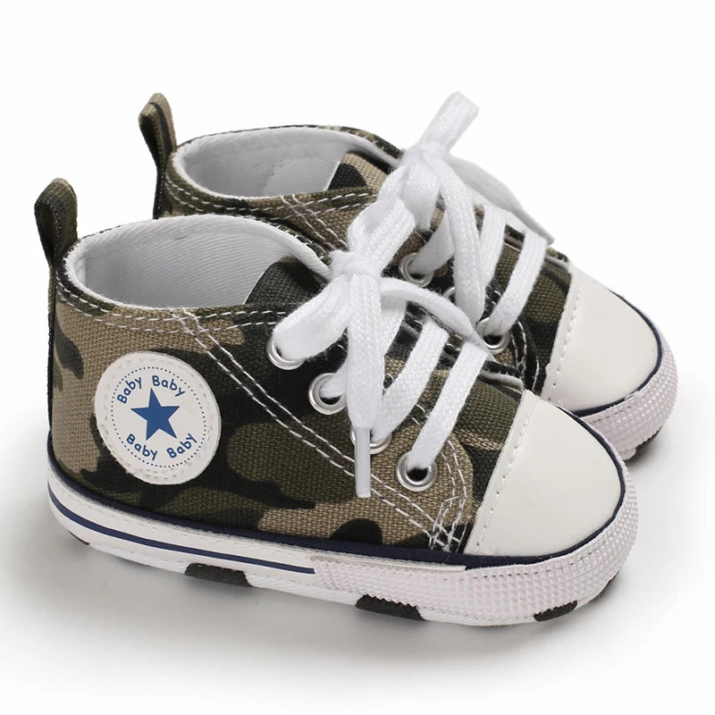 A pair of olive green and white canvas baby shoes with white laces and a camouflage pattern.