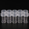 A row of clear plastic storage bottles with screw caps arranged horizontally on a dark surface.