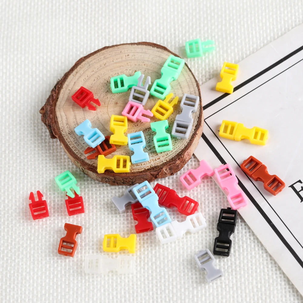 A collection of ten mini plastic buckles in various colors including green, pink, yellow, and red, arranged around a wooden s