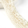 A close-up of multiple strands of faceted crystal glass beads in translucent cream and champagne tones.