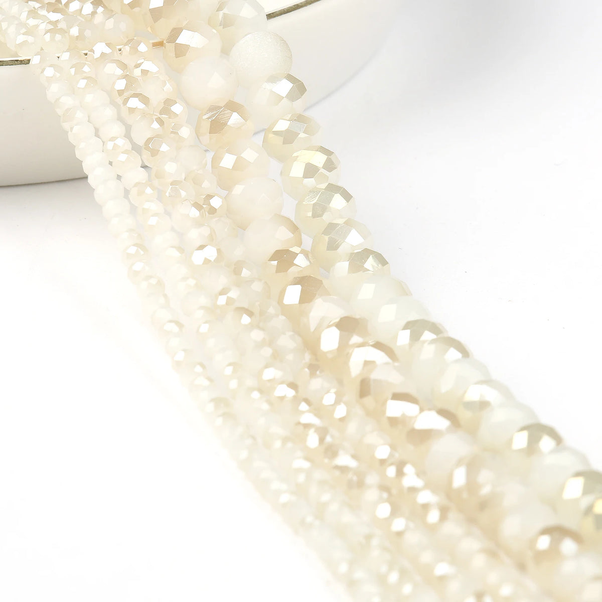 A close-up of multiple strands of faceted crystal glass beads in translucent cream and champagne tones.