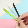 A hand holds three automatic fade pens, one green and two black, resting on pink and blue paper.