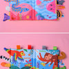 A colorful cloth book featuring sea animals like eel and jellyfish, and a parrot on a pink background.