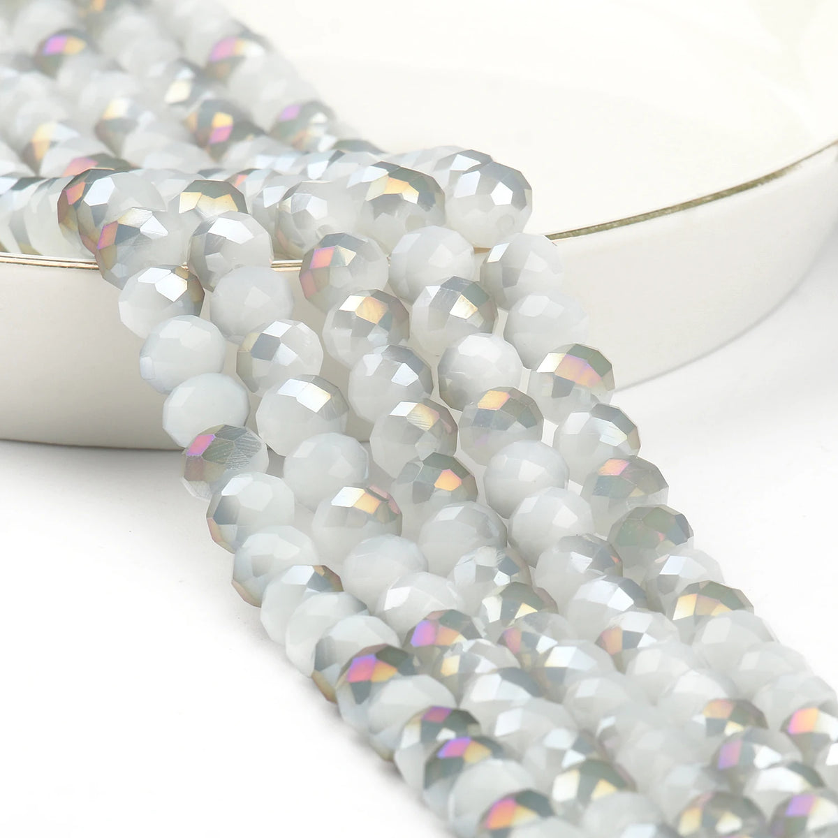 A close-up of a strand of faceted crystal glass beads in iridescent white and silver tones.