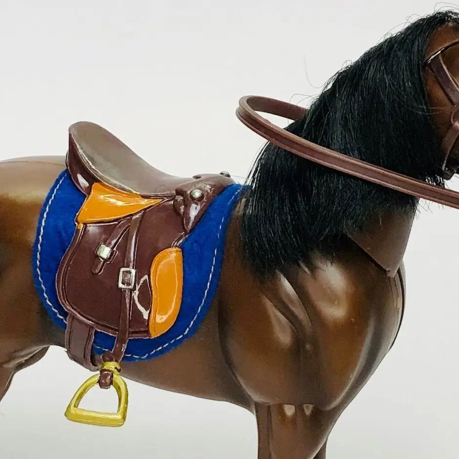A brown horse figurine with a leather saddle and riding prop accessory.