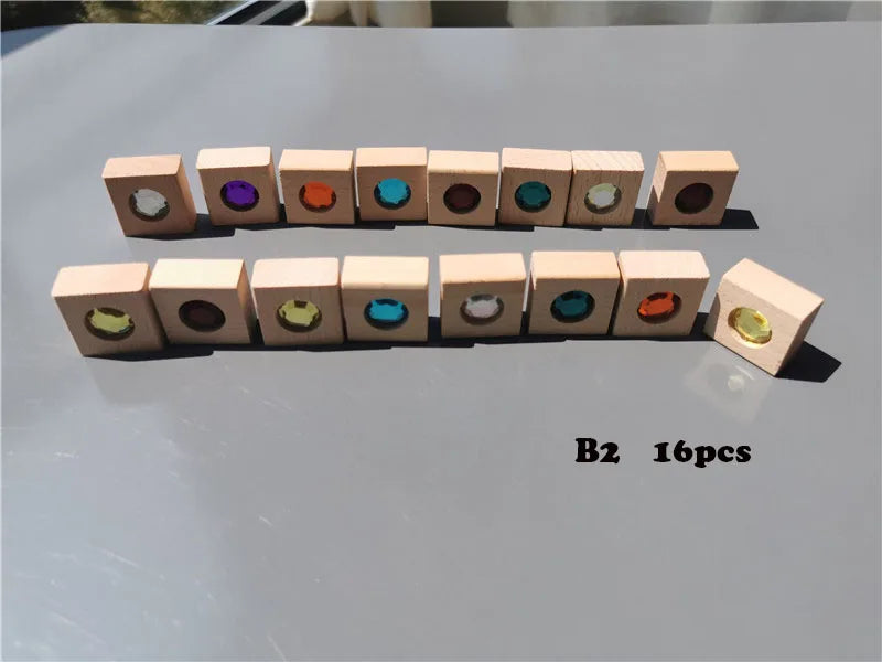 A row of sixteen wooden building blocks, each featuring a colored acrylic gemstone crystal.