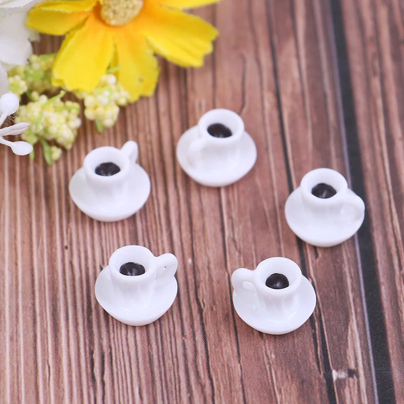 A set of five small white resin coffee cups with black interiors resting on a wooden surface next to a yellow flower.
