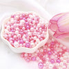 A pile of assorted pink and purple pearl beads for jewelry making displayed in a white dish.
