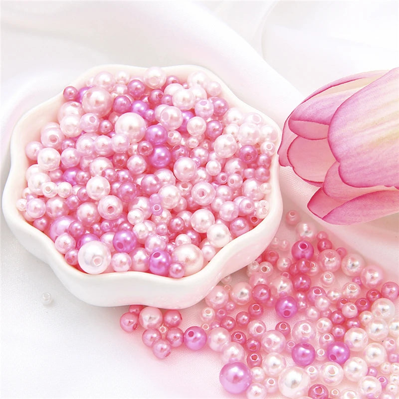 A pile of assorted pink and purple pearl beads for jewelry making displayed in a white dish.