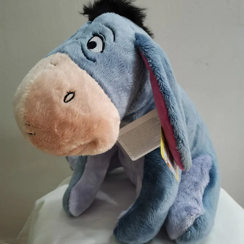 A soft blue Eeyore plush toy resembling a donkey with pink features, shown in a close-up view.