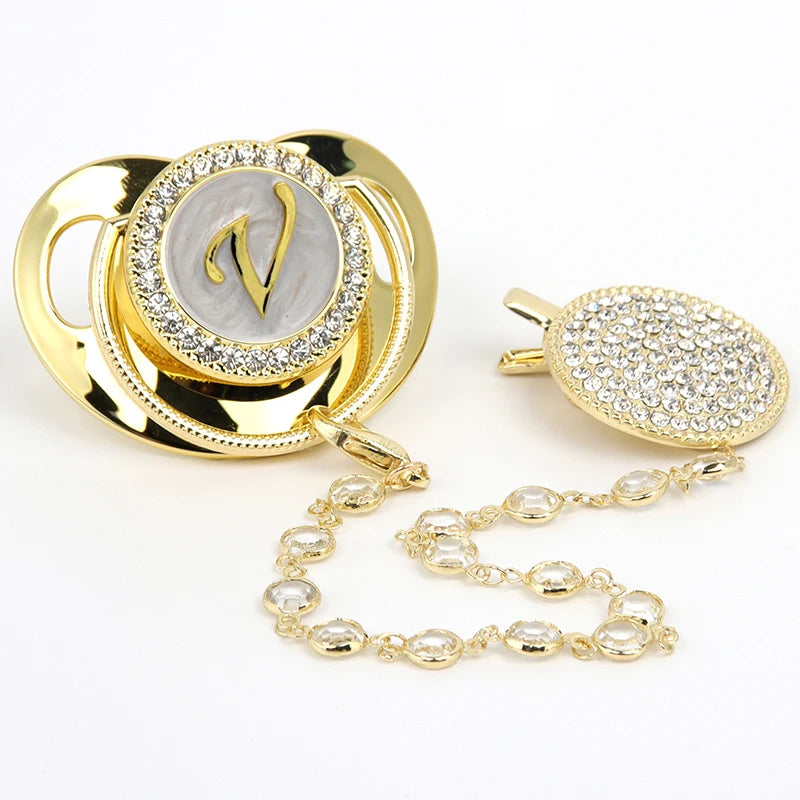 Gold and clear rhinestone pacifier featuring a personalized initial design and clip.