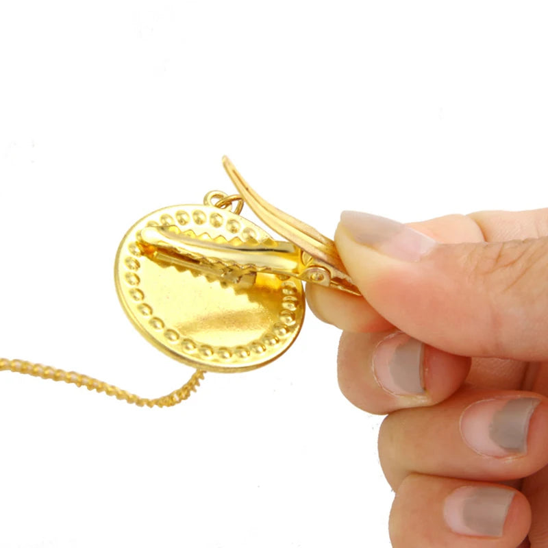 Gold-toned baby pacifier and clip set with rhinestone accents being held by a hand
