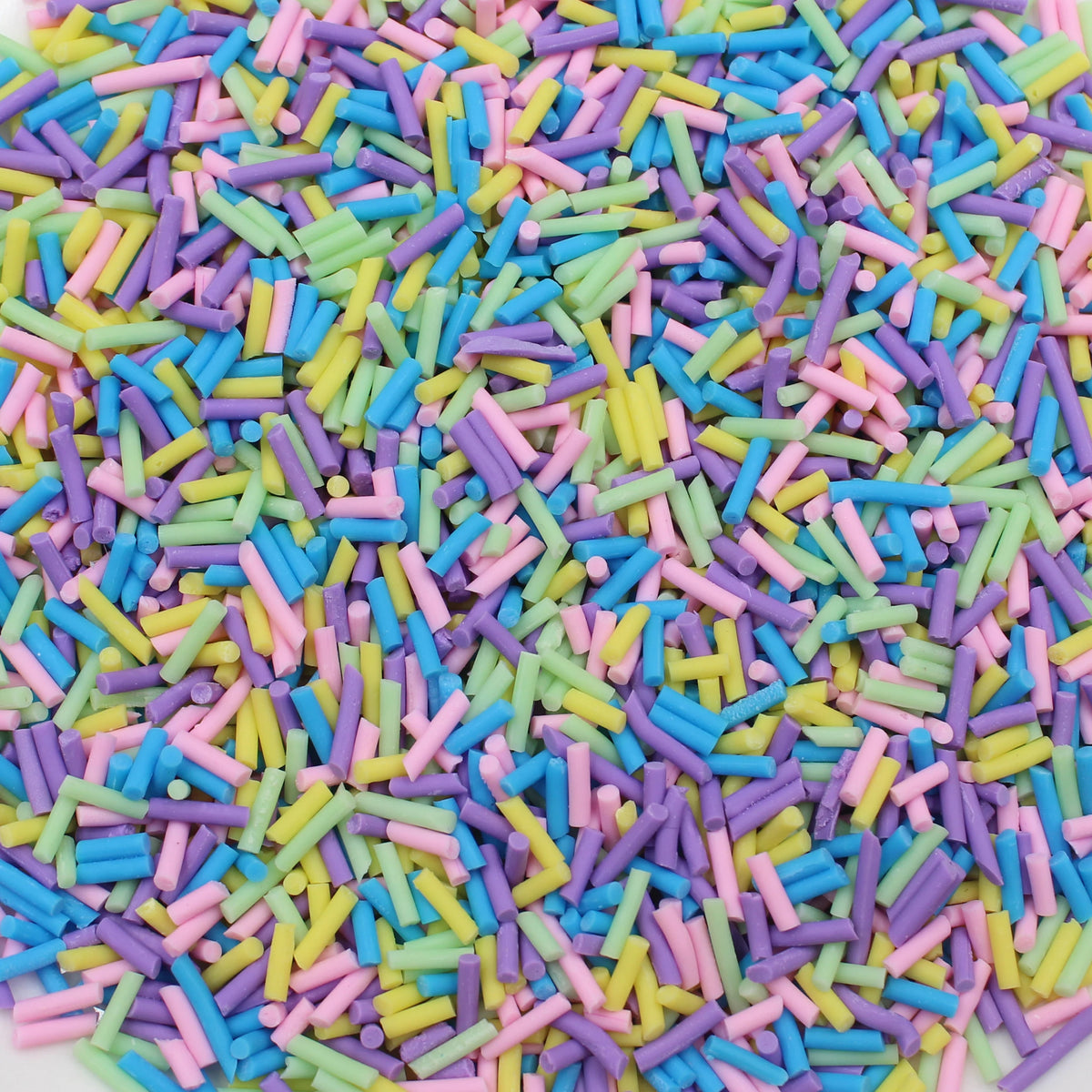 A pile of colorful soft polymer clay candy sprinkles in various shades of pink, blue, yellow, and green.