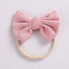 A pink knitted bow headband with a yellow elastic band, suitable for a baby or girl.