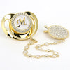 Gold and clear rhinestone pacifier featuring a monogram initial on a silicone clip.