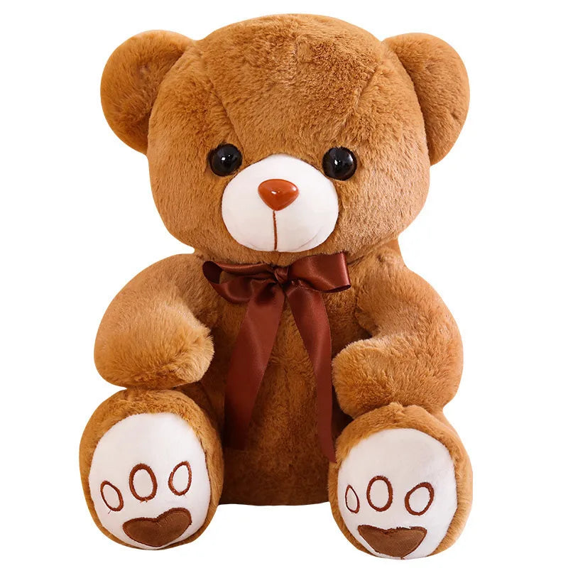 A fluffy brown teddy bear with a stitched orange nose and brown bow.