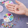 A hand holds a palette of 12-color glass seed beads and loose beads, demonstrating a DIY jewelry making kit.