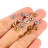 A hand holds several silver and gold Tibetan style hollow flower bead caps for jewelry making.