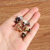 A hand holds several decorative heart brass rivets for leather craft and DIY projects.