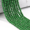 A strand of green faceted crystal glass beads laid across a white surface.