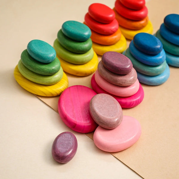 A colorful stack of wooden rainbow stacking blocks in various shades of green, yellow, orange, and blue.