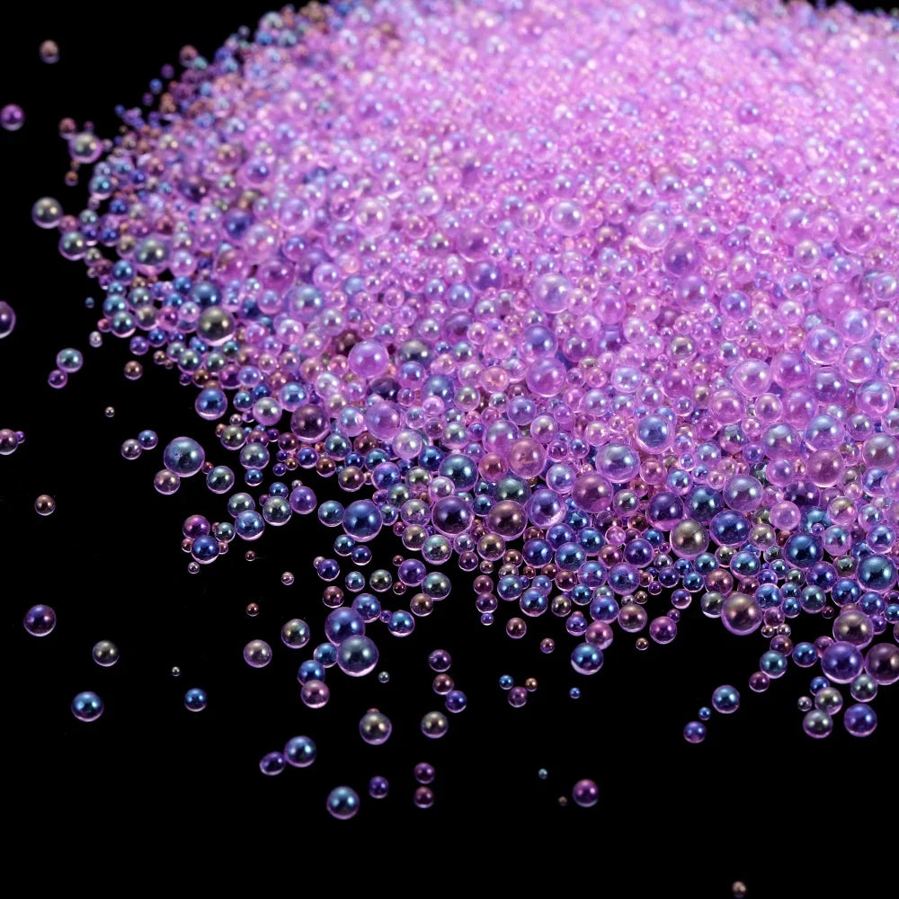 A pile of iridescent purple and pink mini glass bubble beads scattered against a black background.