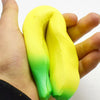A hand holds a yellow and green squishy banana stress reliever toy.