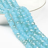 A close-up of light blue faceted crystal glass beads strung together for jewelry making.