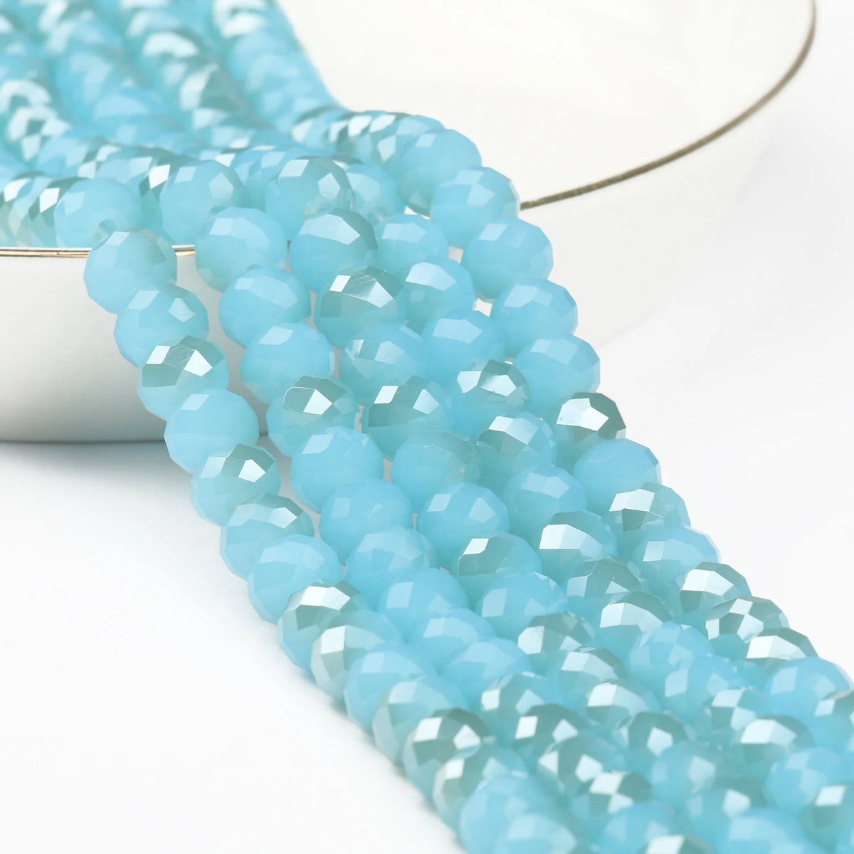 A close-up of light blue faceted crystal glass beads strung together for jewelry making.