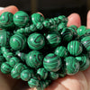 A handful of small green and black striped gemstone beads for jewelry making