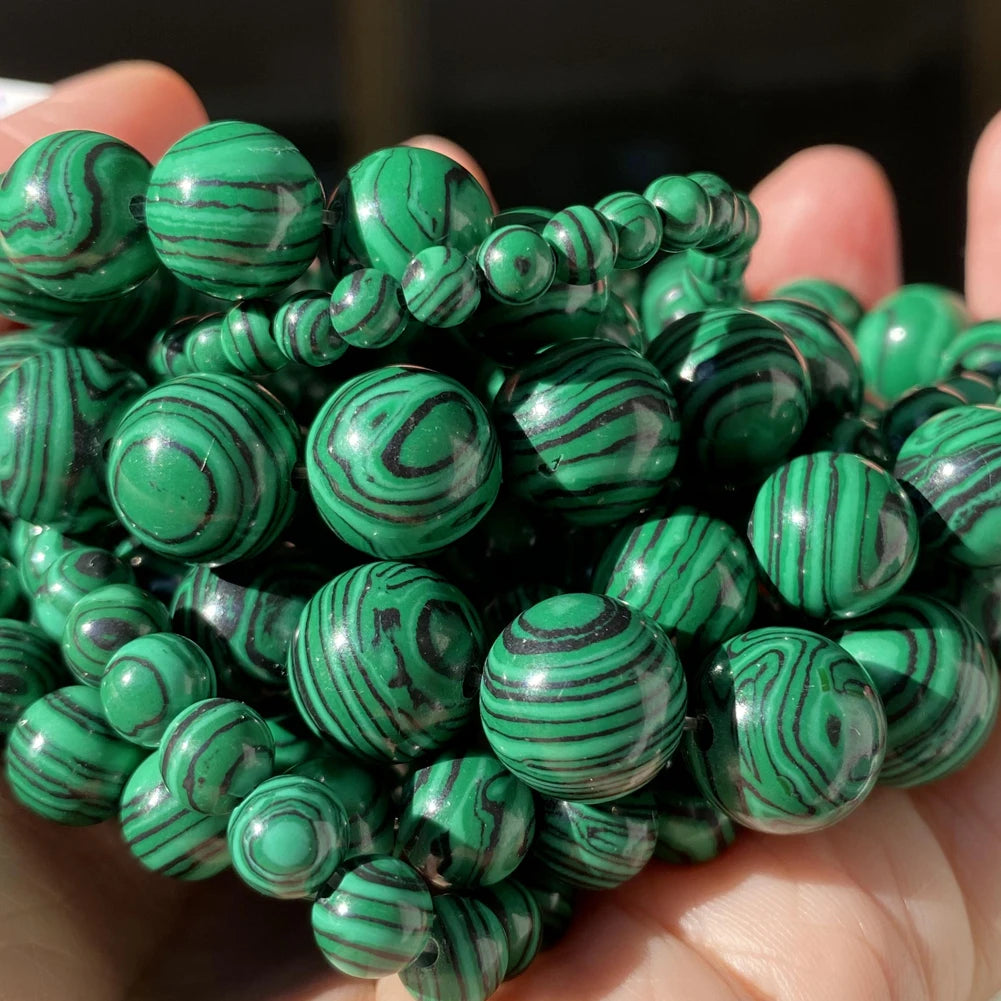 A handful of small green and black striped gemstone beads for jewelry making