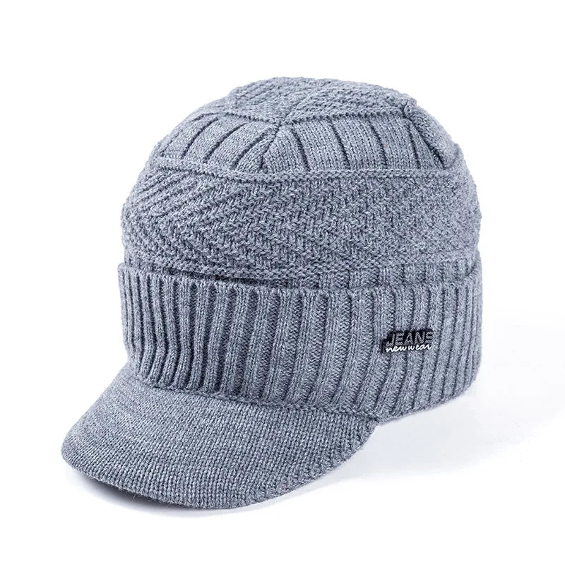 A gray knit beanie with a brim is shown, featuring a ribbed texture and a small logo.