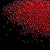 A pile of small, translucent red glass bubble beads scattered against a black background.