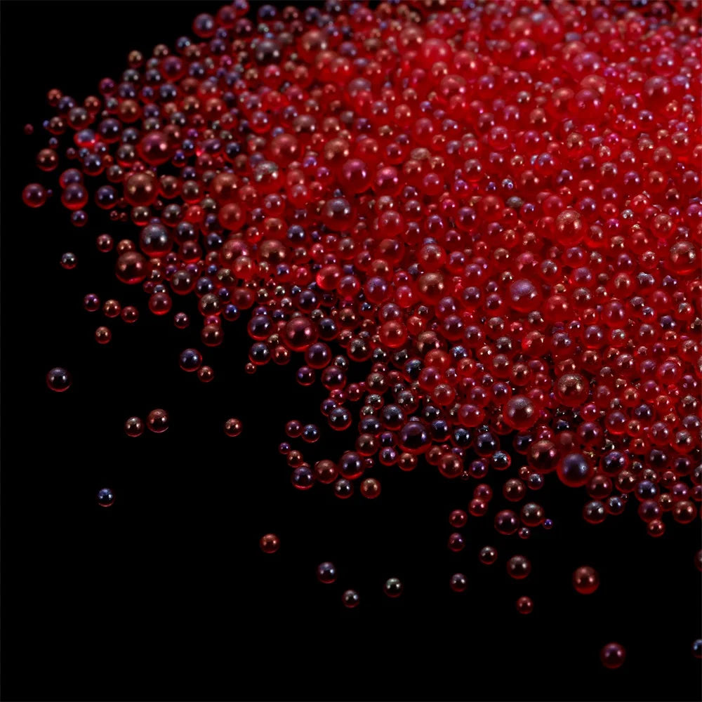 A pile of small, translucent red glass bubble beads scattered against a black background.